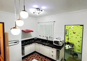 a kitchen with white cabinets and a sink and a refrigerator at Cantinho de Maria in Aparecida +33 photos
