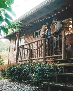 dos personas de pie en un balcón de una casa en Cabañas La Silleta en Santa Elena