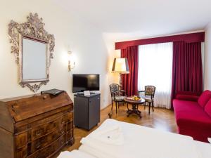 Habitación de hotel con sofá rojo y TV en Hotel Royal, en Viena