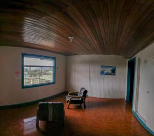 a living room with a wooden ceiling and a chair at Geliwa B&B in Turrialba