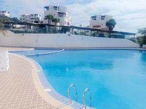 une grande piscine bleue avec des bâtiments en arrière-plan dans l'établissement Charmant Studio piscine mdiq CaboNégro Martil, à Cabo Negro
