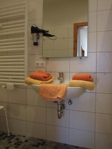 ein Badezimmer mit einem Waschbecken, einem Spiegel und Handtüchern in der Unterkunft Haus Sommerwind in Norderney