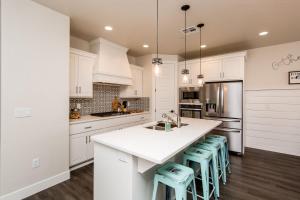 una cocina con armarios blancos y una isla de cocina con taburetes en Town Center 2387 Red Canyon Family Home, en Washington