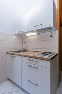 a white kitchen with a sink and a stove at Apartment Pisak 5975d in Pisak