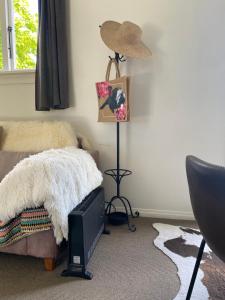 a bedroom with a bed and a hat and a lamp at Glenie Cottage BnB Guesthouse in Timaru