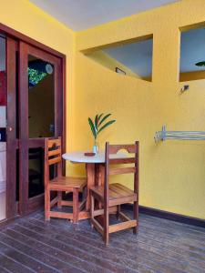 a table and chairs in a room with a yellow wall at Pousada do Tio Zé in Itacaré