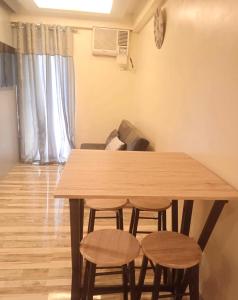 a wooden table with four chairs in a living room at Allen’s cozy condo in Davao City
