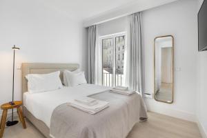 um quarto branco com uma cama grande e um espelho em Les Deux Mariettes São Bento em Lisboa