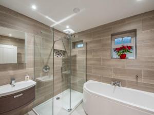 a bathroom with a shower and a tub and a sink at Fir Cottage - Uk38485 in Saltash