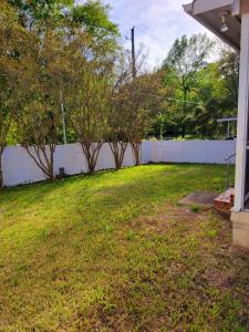 a yard with a white fence and some trees at Convenient and Comfortable in Macon