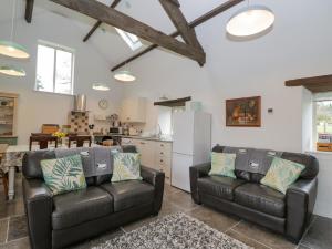 a living room with two leather couches and a kitchen at Oxbarton in Butcombe