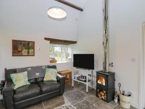 a living room with a leather couch and a fireplace at Oxbarton in Butcombe