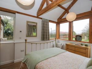 a bedroom with a bed and a desk and windows at Oxbarton in Butcombe
