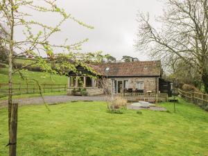 a stone house with a yard in front of it at Oxbarton in Butcombe