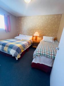 a room with two beds and a table with a lamp at Glenview Cottages in Sault Ste. Marie