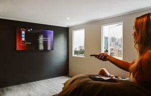 a woman sitting on the floor watching a tv at Nate's Place Backpackers Sydney in Sydney