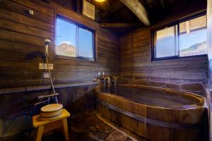 a wooden bathroom with a tub and windows at Ryosou Makibanoie 18 years or older in Yufuin