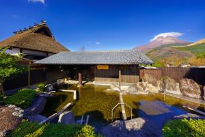 a house with a pond in front of a mountain at Ryosou Makibanoie 18 years or older in Yufuin