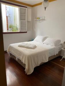 uma cama branca num quarto com uma janela em Solar Antônio Dias em Ouro Preto
