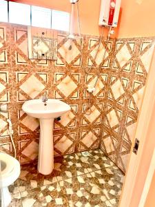 een badkamer met een witte wastafel en een betegelde muur bij Medano Sunset Resort in Mambajao