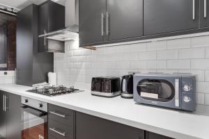 a kitchen with a toaster oven and a microwave at Sleep14 in Victoria London 43VPR in London