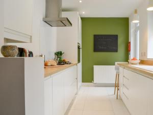 a kitchen with white cabinets and a green wall at Hulne House in Alnwick