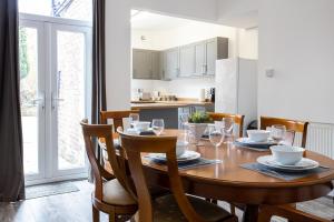 cocina y comedor con mesa de madera y sillas en Cheadle village en Cheadle