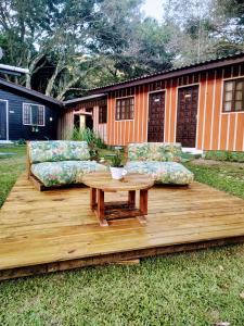 una terrazza in legno con 2 divani e un tavolo di Pousada Recanto das Cores a Ilha do Mel