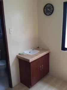 baño con lavabo y reloj en la pared en JW Apartments en Ángeles