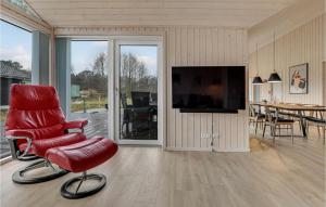 a living room with a red chair and a television at Nice Home In Aakirkeby With Wifi And 3 Bedrooms in Vester Sømarken