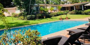 a swimming pool in a yard with chairs and a house at Casa Gabriela para gozar con los tuyos-piscina con calefacción in Cuernavaca