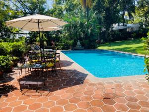 a table with an umbrella next to a swimming pool at Casa Gabriela para gozar con los tuyos-piscina con calefacción in Cuernavaca