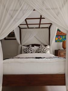 1 dormitorio con cama con dosel y cortinas blancas en Raaga Samudra Villa en Padangbai