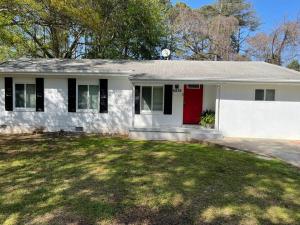 a white house with a red door and a yard at Four Bedroom Home Near Hartsfield Jackson Airport in Riverdale