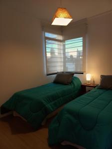 een slaapkamer met 2 groene bedden en een raam bij La Josefina in Tandil