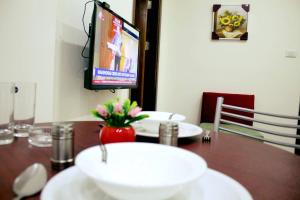 a dining room table with a television and a vase of flowers at شقق مرحبا المفروشة marhaba furnished apartment in Amman