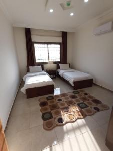 a bedroom with two beds and a rug at شقق مرحبا المفروشة marhaba furnished apartment in Amman