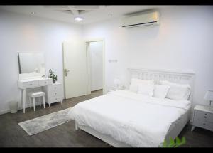 شقة جديدة ومفروشة للايجار اليومي والشهري في محافظة الرس في الرس: غرفة نوم بيضاء مع سرير أبيض ومغسلة