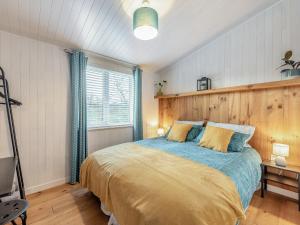 a bedroom with a large bed with blue and yellow sheets at Heather Lodge in Willington