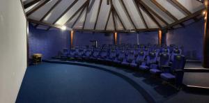 an auditorium with blue chairs in a room with a stage at Hotel Terramia Resort in Santa Cruz de la Sierra
