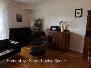 ein Wohnzimmer mit 2 Stühlen und einem Schreibtisch in der Unterkunft Homestay - Yarra River Boulevard in Melbourne