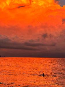 a person riding a wave in the ocean at sunset at Wan Ning Xiao Gang Guest House in Wanning