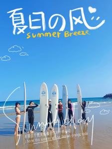a group of people standing on the beach with surfboards at Wan Ning Xiao Gang Guest House in Wanning