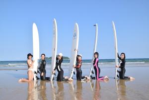 un grupo de mujeres de pie en la playa con tablas de surf en Wan Ning Xiao Gang Guest House, en Wanning