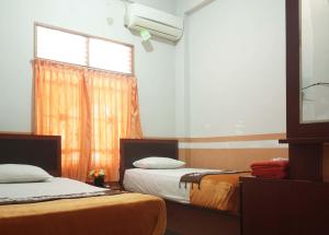 Hotel Al Madinah Bangkinang في Bangkinang: غرفة بسريرين ونافذة