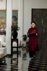 een vrouw die door een kamer loopt met een bord in haar hand bij aNhill Boutique in Hue