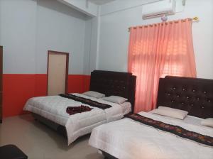 Hotel Al Madinah Bangkinang في Bangkinang: غرفة نوم بسريرين ومرآة ونافذة