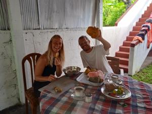un hombre y una mujer sentados en una mesa con comida en Ocean edge villa, en Midigama East