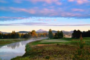 un campo de golf con un estanque y montañas al fondo en Sunriver Resort, en Sunriver