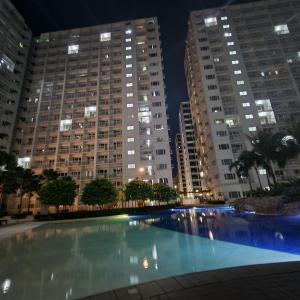 uma grande piscina à noite com edifícios altos em EZStays Shore Residences em Manila